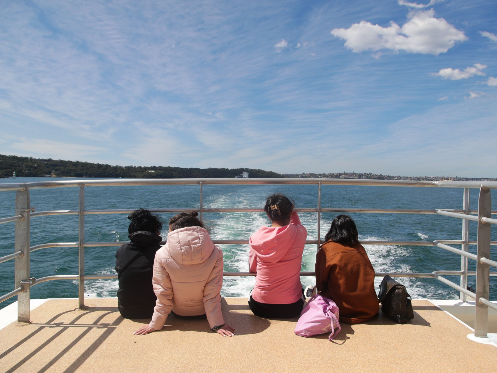 a woman sitting on a bench next to a body of water