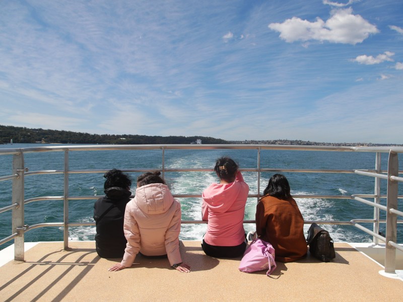 a woman sitting on a bench next to a body of water