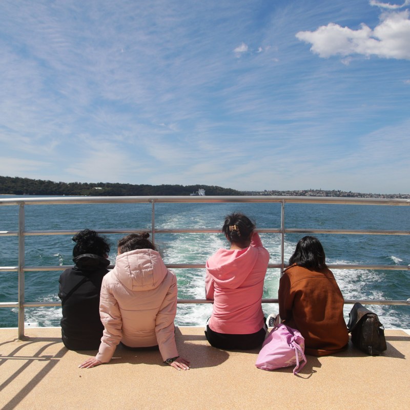 a woman sitting on a bench next to a body of water