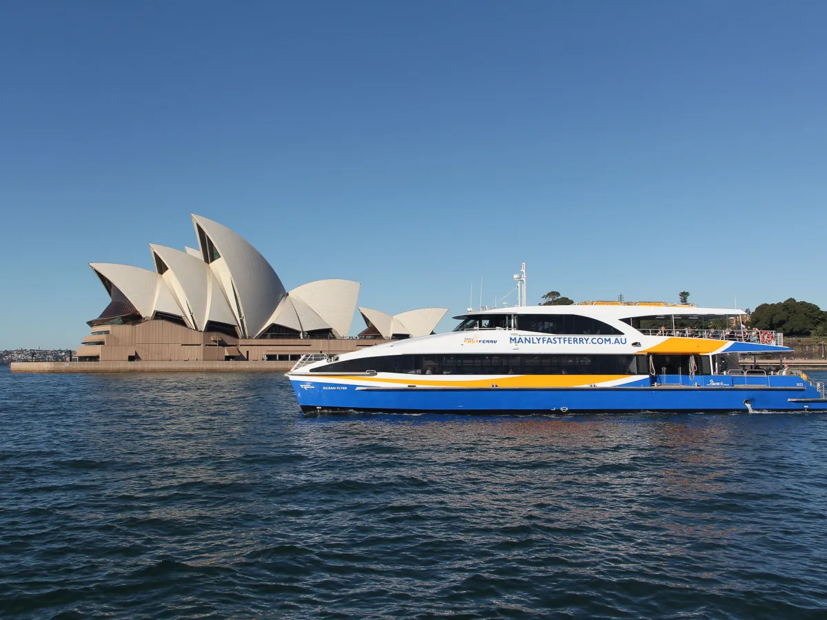 a small boat in a large body of water with Sydney Opera House in the background