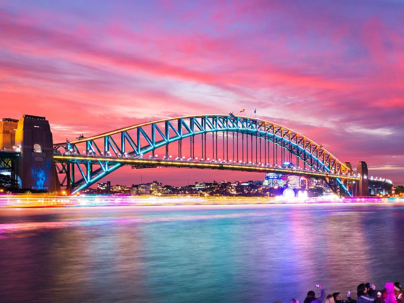 Families enjoying the illuminated Sydney Harbour Bridge during a VIVID Sydney cruise.