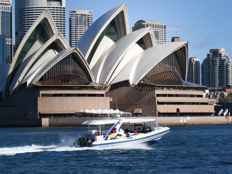 a large ship in a body of water with Sydney Opera House in the background