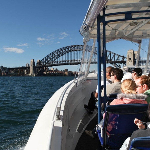 a man standing in front of a boat next to a body of water