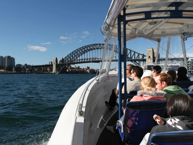 a man standing in front of a boat next to a body of water