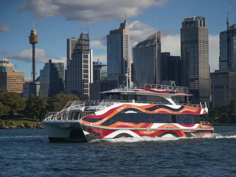 a large ship in a body of water with a city in the background