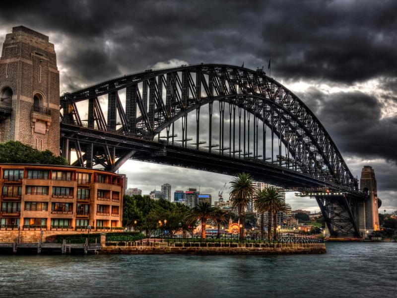 a train crossing Sydney Harbour Bridge over a river in a city