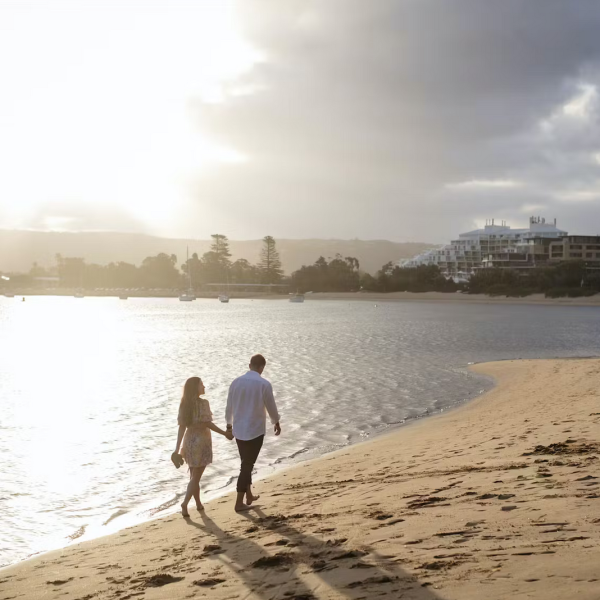 a man walking across a beach next to a body of water