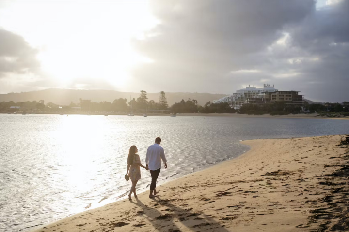 a man walking across a beach next to a body of water