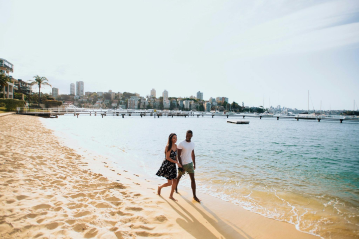 a man and woman walking across a beach next to the water