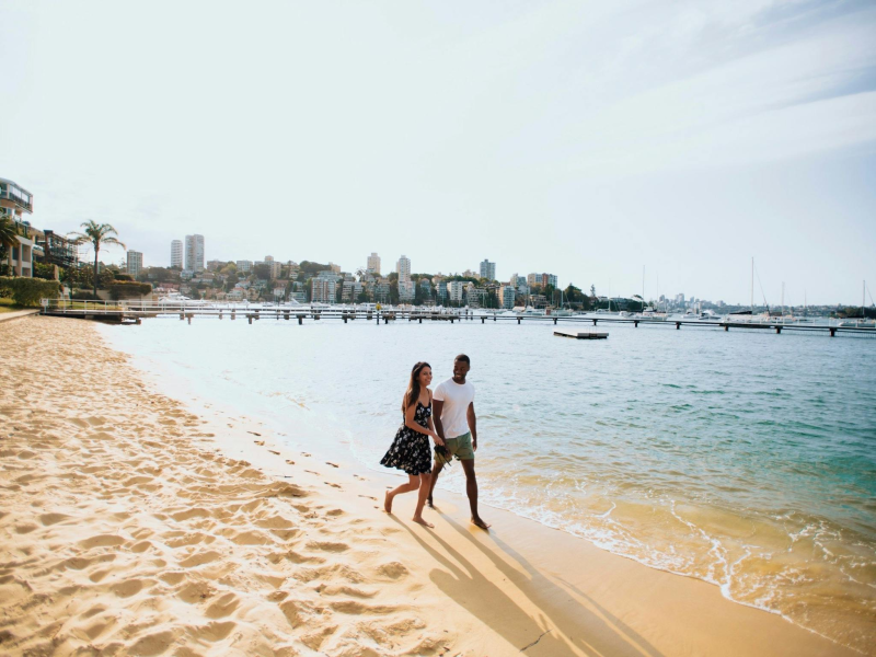a man and woman walking across a beach next to the water