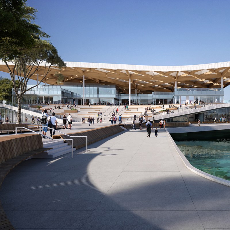 Modern building with angular roof, people walking, and a waterfront path.