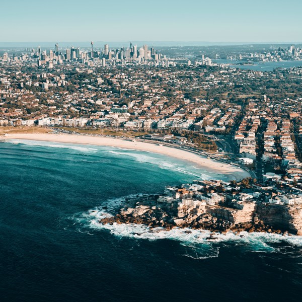 Aerial view of a beach with cityscape in the background on a clear day.