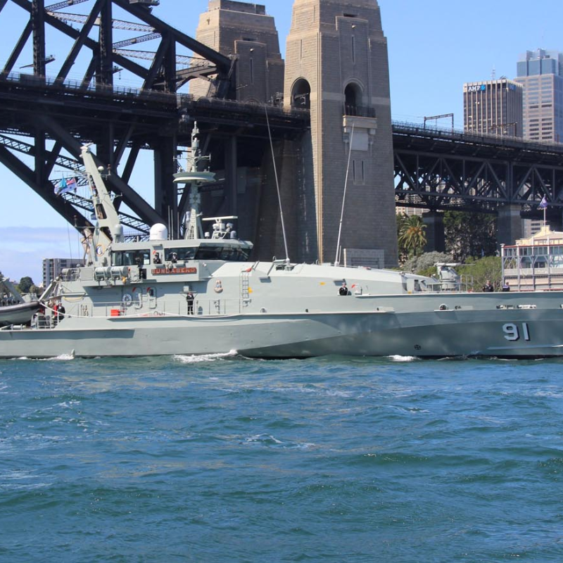 Patrol boat 91 on water in front of a large iron bridge and city skyline.