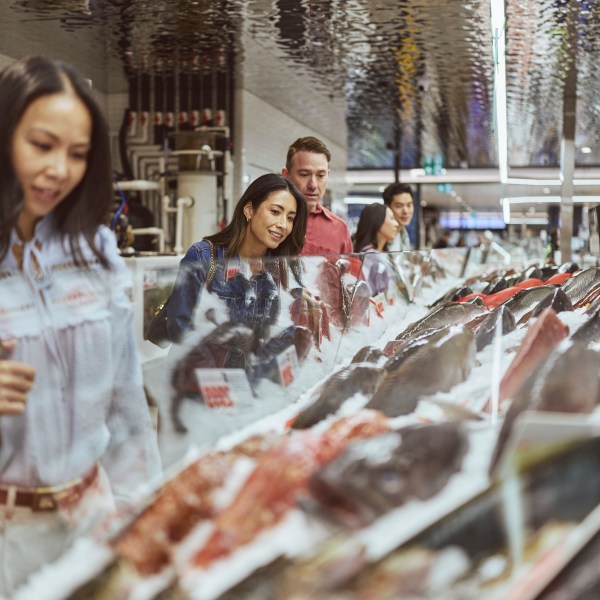 People looking at seafood display in a market.